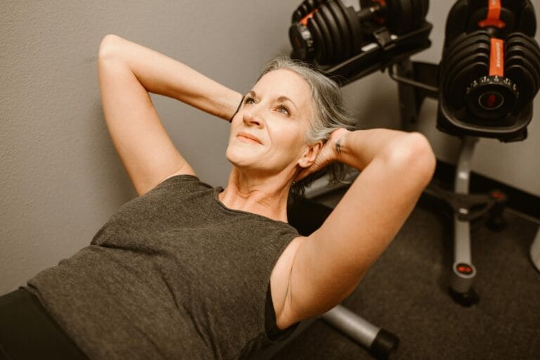 A senior woman performing exercises with dumbbells in a modern fitness center, promoting active lifestyle.